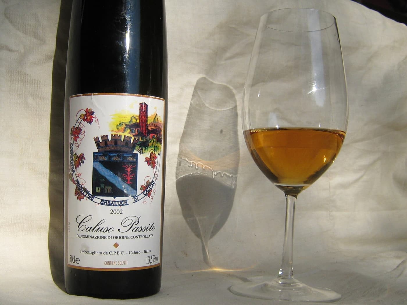 Photo of bottle and glass of passito dessert wine from Caluso in Northern Italy, nicely showing wine legs